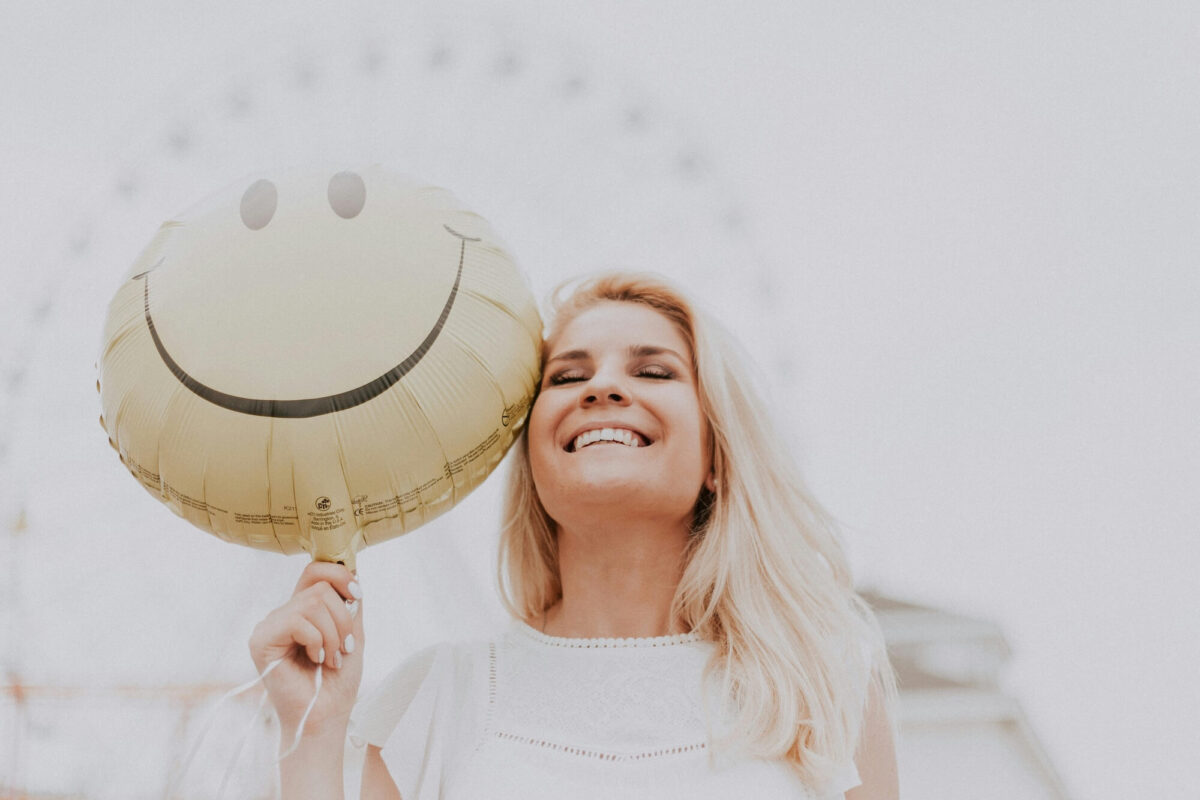Beautiful smiling woman holding happy face ballon